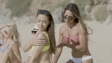 Side-view-of-Hispanic-girl-putting-sunscreen-on-friends-back